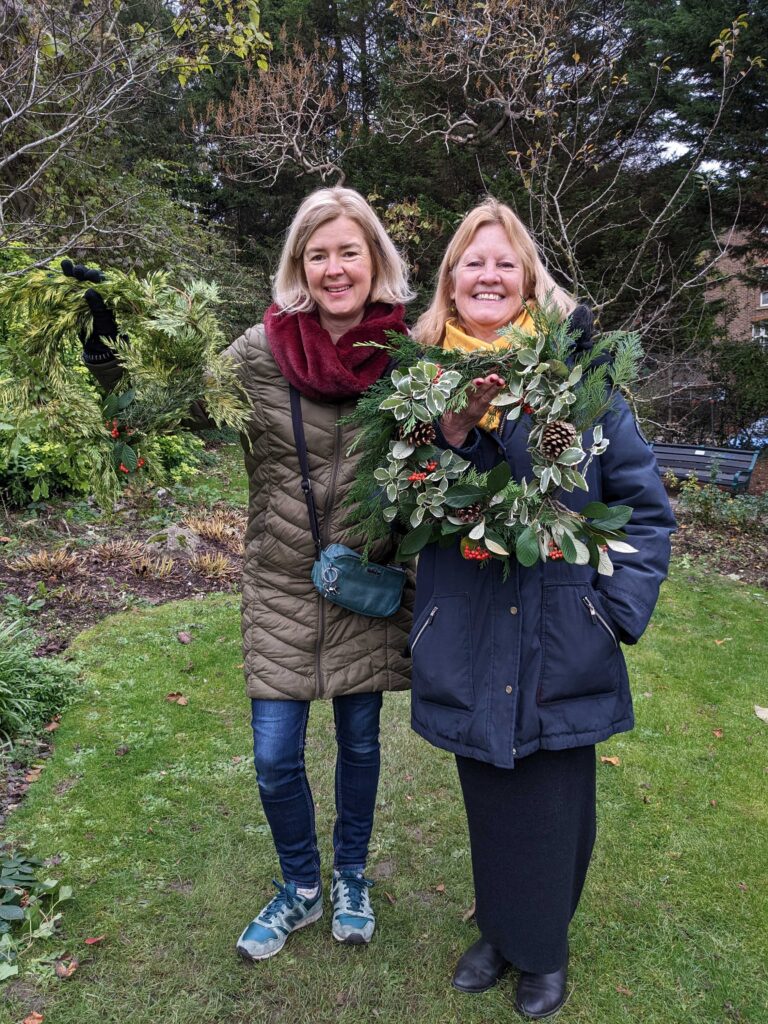 two ladies holding christmas wreaths