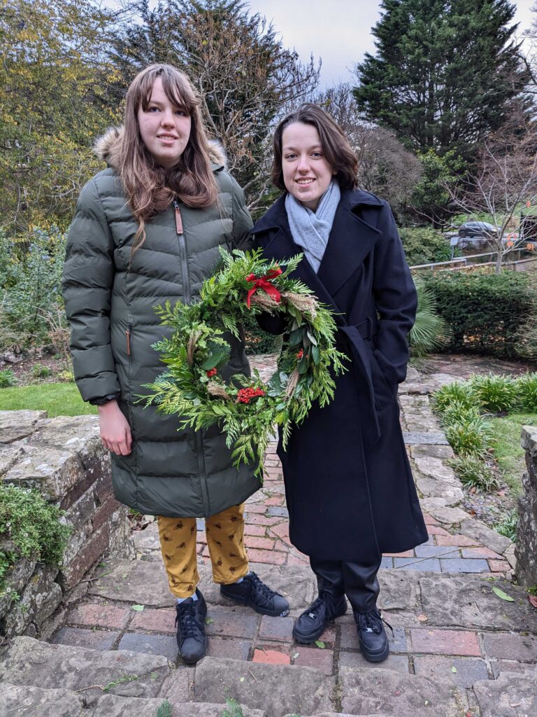 two ladies holding a christmas wreath